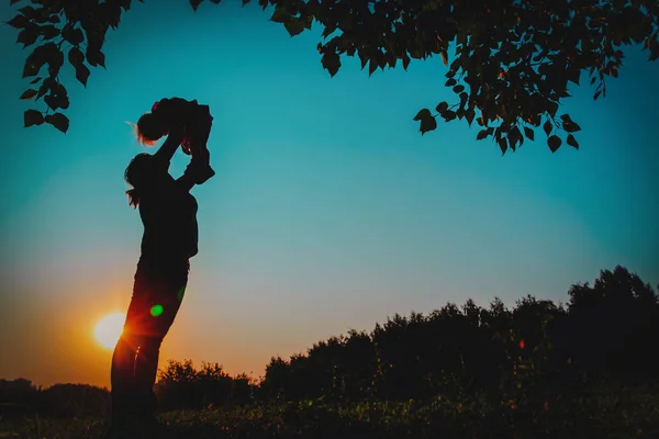 Happy mother and little daughter play at sunset — Stock Photo, Image