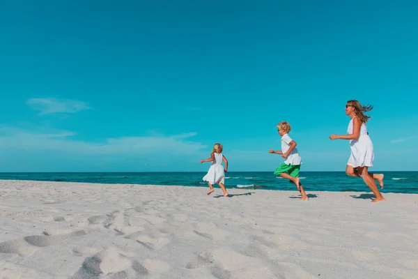 Moeder met kinderen spelen looppas op tropisch strand — Stockfoto