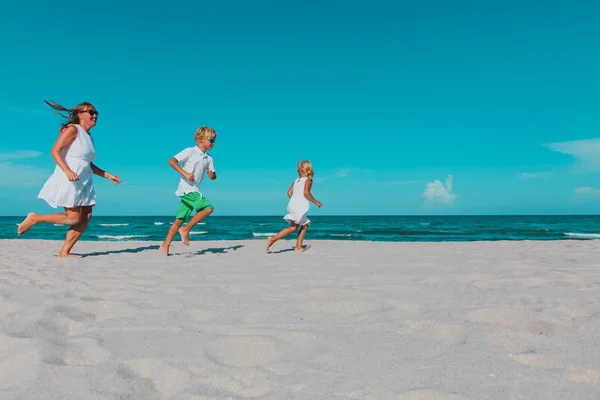 Moeder met kinderen spelen looppas op tropisch strand — Stockfoto