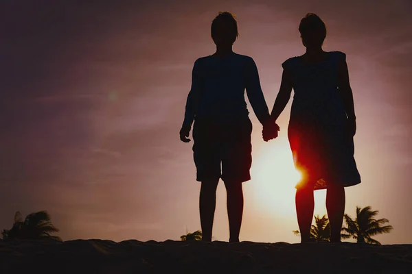 Lyckliga älskande par hålla händerna på sunset beach — Stockfoto