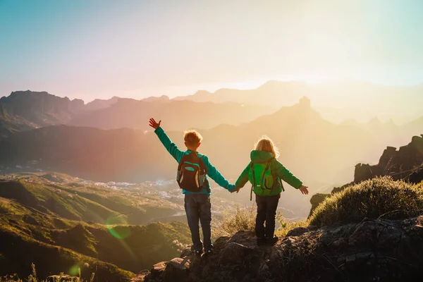 Счастливые мальчик и девочка путешествуют в горах на закате, дети любят походы — стоковое фото