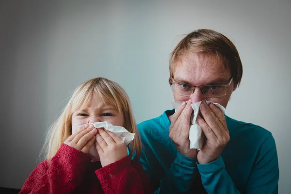 father and daughter wiping and blowing nose, infection or allergy
