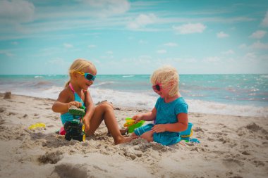 küçük kızlar sahilde kum ile oynamak