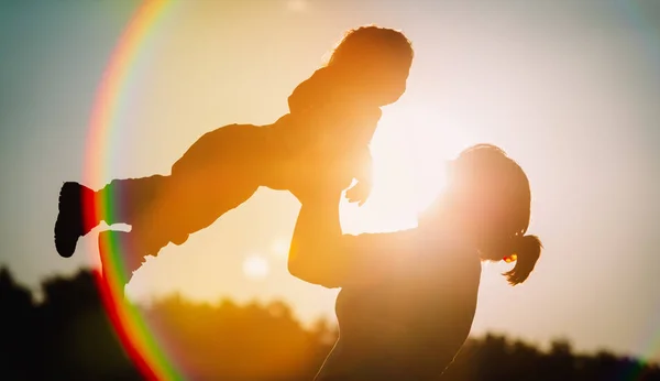 Anne ve küçük kızı günbatımı gökyüzüne, aile sevgisi kavramı oynamak — Stok fotoğraf