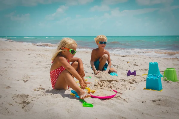 Mignon garçon et fille jouer avec sable sur la plage — Photo