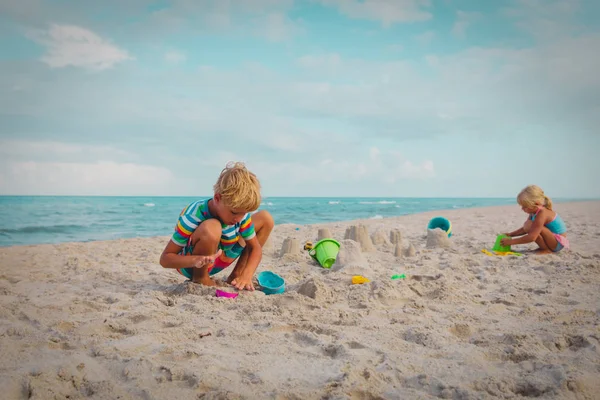 Menino e menina jogar com areia na praia — Fotografia de Stock
