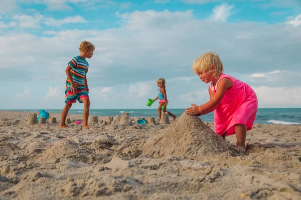 Enfants jouent avec le sable sur la plage, bâtiment familial château de sable — Photo