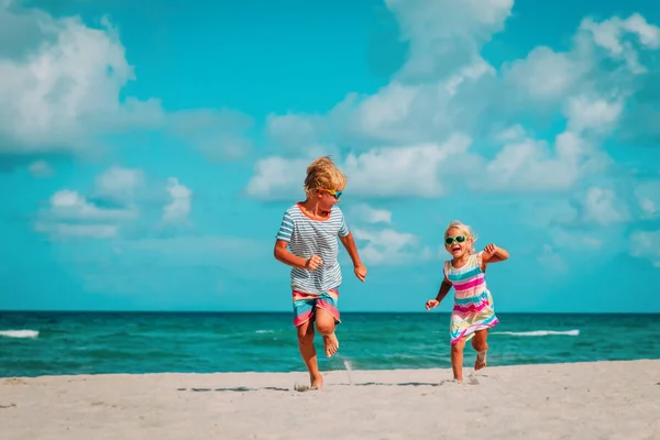 Счастливые дети мальчик и девочка бегают по пляжу — стоковое фото