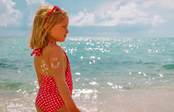 Sonnenschutz am Strand - kleines Mädchen mit Sonnencreme auf der Schulter — Stockfoto