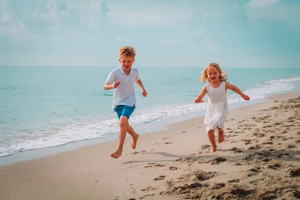 Счастливые мальчик и девочка бегают по пляжу, семья наслаждается отдыхом на море — стоковое фото