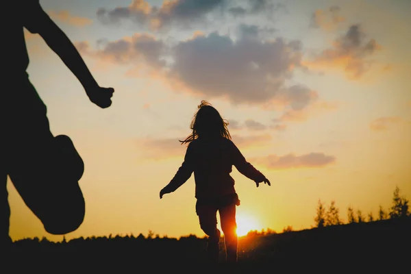 Silhuetten av glad flicka och pojke kör vid solnedgången — Stockfoto