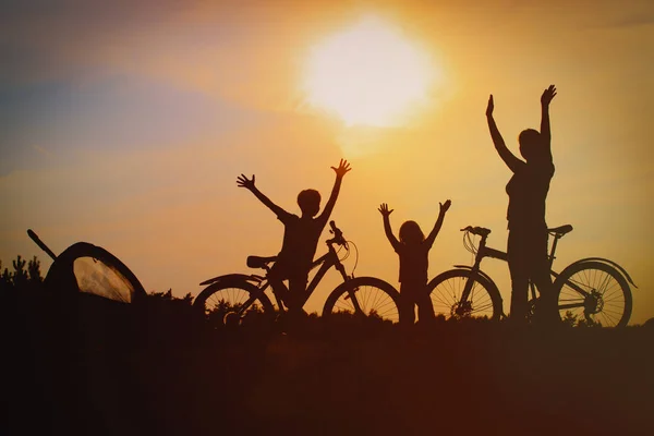 Mãe feliz com crianças de bicicleta ao pôr do sol — Fotografia de Stock