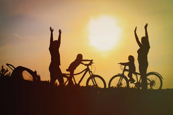 Mãe feliz, pai com crianças de bicicleta ao pôr-do-sol — Fotografia de Stock