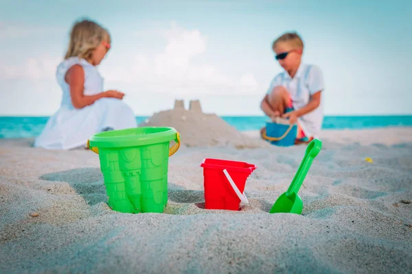 Speelgoed en kinderen-jongen en meisje-spelen met zand op strand — Stockfoto