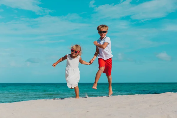 Gelukkige jongen en meisje lopen op het strand, kinderen spelen op vakantie — Stockfoto