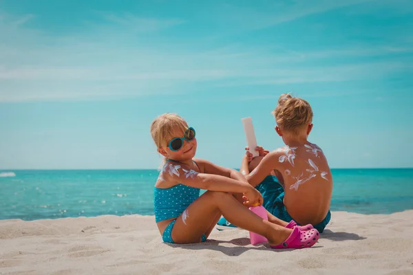 Güneşten korunma, kız ve erkek plajda krem güneş kremi ile — Stok fotoğraf