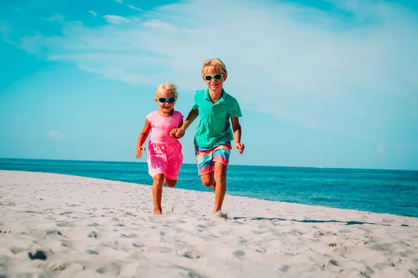 Šťastný chlapec a dívka běžet na pláži, děti hrají na dovolené — Stock fotografie