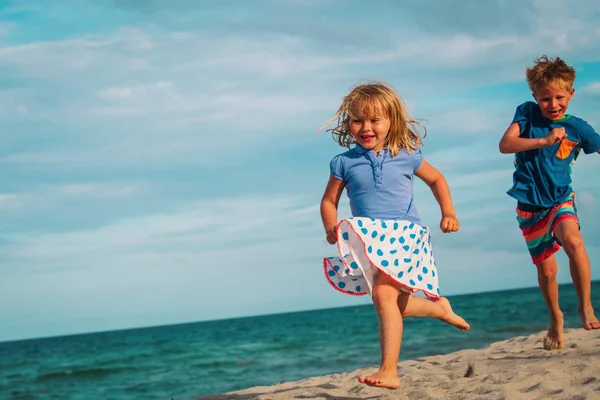 Счастливые мальчик и девочка, бегущие по пляжу — стоковое фото