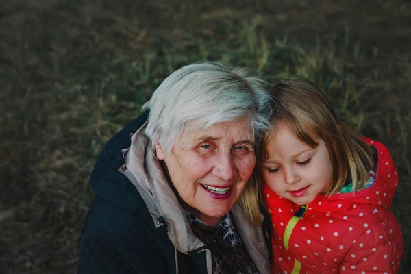 Happy grandmother and granddaughter hug in nature — Stock Photo, Image