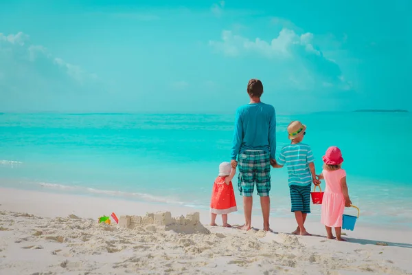 Padre con tre figli gioca in spiaggia, famiglia al mare — Foto Stock