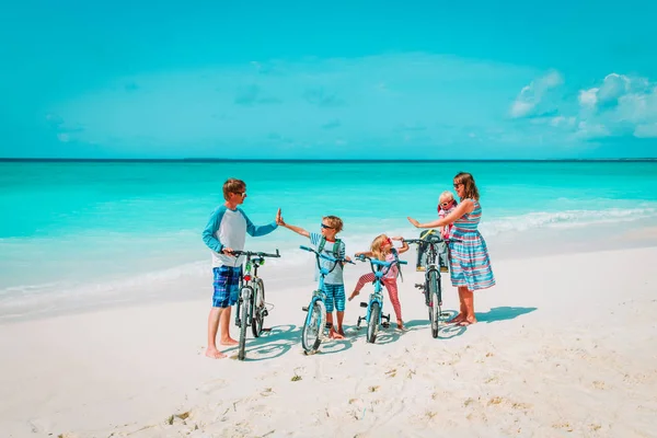 Счастливая молодая семья с детьми на велосипедах на пляже — стоковое фото