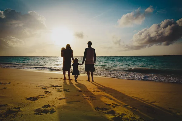 Família feliz com criança jogar na praia do pôr do sol — Fotografia de Stock