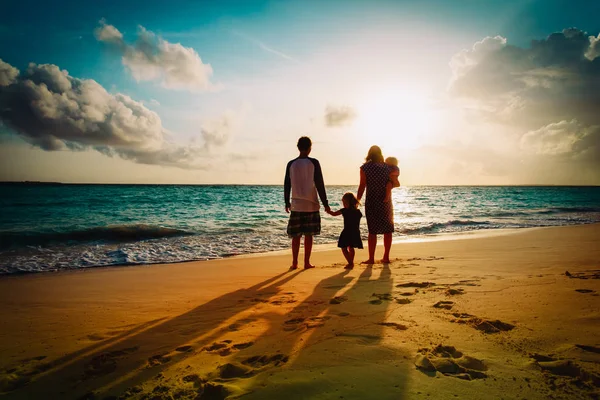 Счастливая семья с ребенком играют на пляже заката — стоковое фото