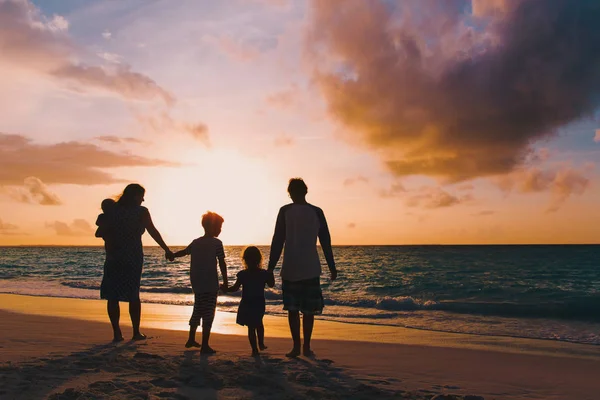 Familia feliz con los niños del árbol caminan en la playa del atardecer — Foto de Stock