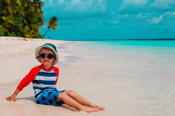 Милый мальчик играет с водой и песком на пляже — стоковое фото