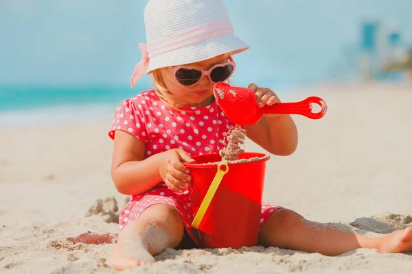 Schattig klein meisje spelen met zand en speelgoed op strand — Stockfoto