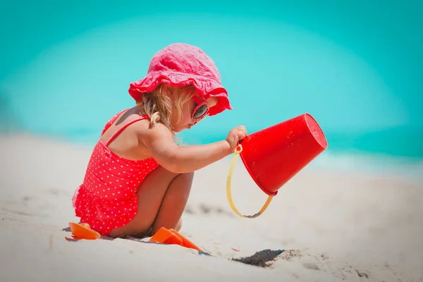 Милая маленькая девочка играет с песком и игрушками на пляже — стоковое фото