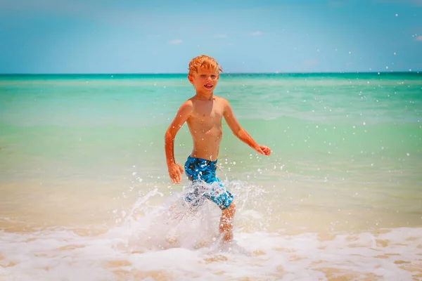 Menino feliz executar jogar com ondas na praia — Fotografia de Stock