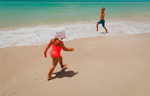Ittle niño y niña jugar con agua en la playa —  Fotos de Stock