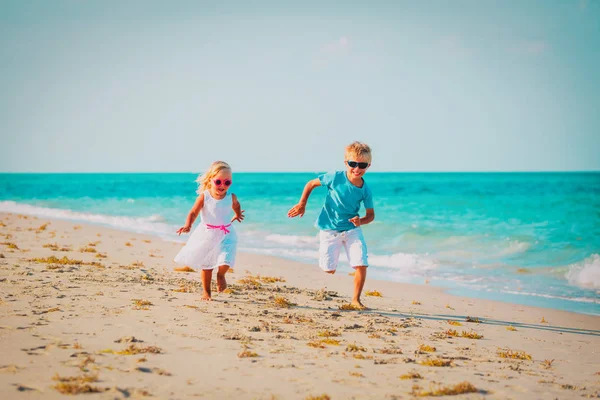 Chlapeček a dívka, co běží na dovolenou na pláži — Stock fotografie