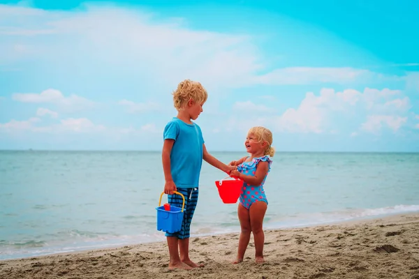 Malý chlapec a dívka hrát s pískem na pláži — Stock fotografie