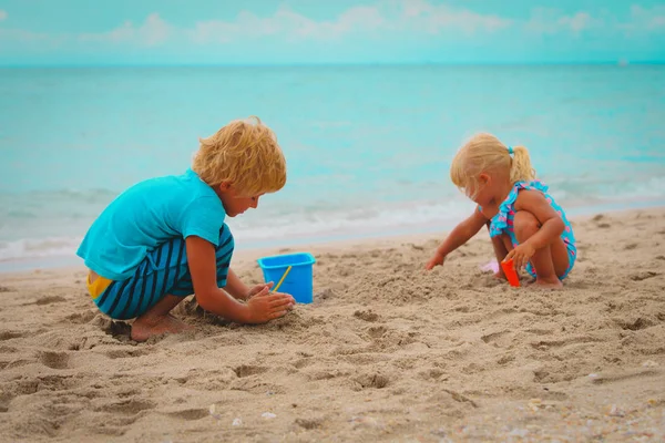 Мальчик и девочка играют с песком на пляже — стоковое фото