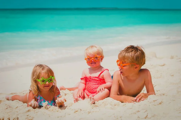 Schattige kleine jongen en meisjes spelen met zand op strand — Stockfoto