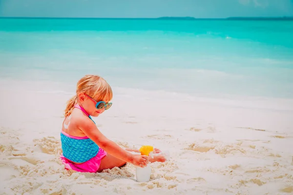 Zon bescherming-klein meisje met zonnebrandcrème op strand — Stockfoto