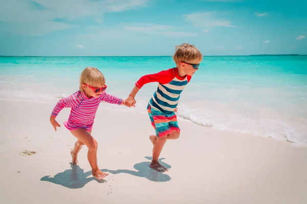 Niño y niña corren en la playa, los niños juegan de vacaciones —  Fotos de Stock