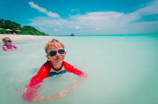 Mały chłopak i dziewczyna pływać na tropikalnej plaży — Zdjęcie stockowe