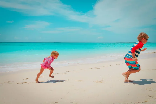 Chlapeček a děvče jezdí na pláži, děti hrají na dovolené — Stock fotografie