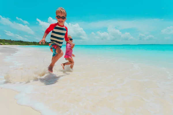 Niño y niña corren en la playa, los niños juegan de vacaciones —  Fotos de Stock