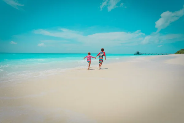 Menino e menina correr na praia, as crianças brincam de férias — Fotografia de Stock