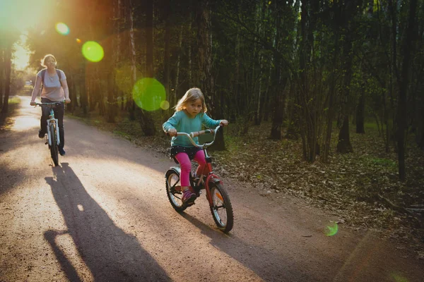 Madre e figlia in sella a biciclette nella natura al tramonto — Foto Stock