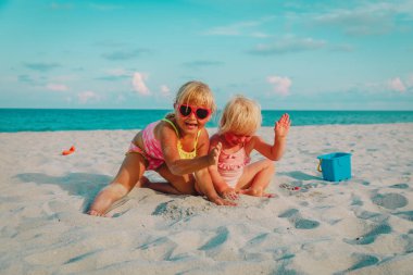 Çocuklar yaz plajında kumla oynarlar.