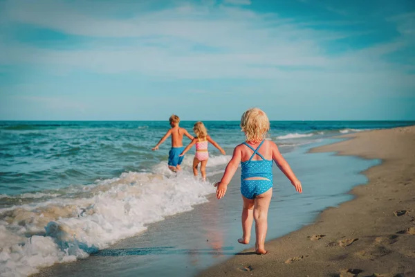 Дети веселятся на пляже, всей семьей играют с волнами — стоковое фото