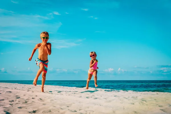 Szczęśliwy ładny chłopak i dziewczyna biegać na plaża — Zdjęcie stockowe