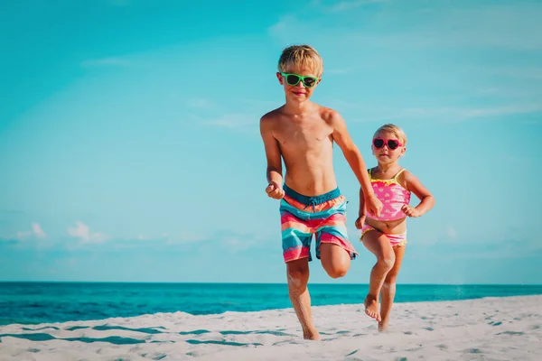 Šťastný chlapec a děvče jezdí na pláži — Stock fotografie