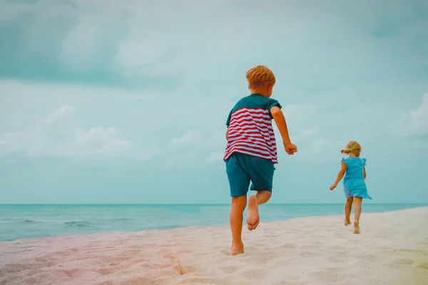 Lycklig pojke och flicka köra på stranden — Stockfoto