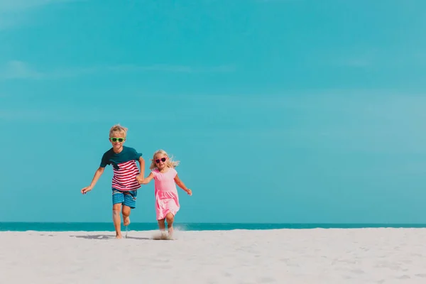 Gelukkig schattig jongen en meisje lopen op het strand — Stockfoto